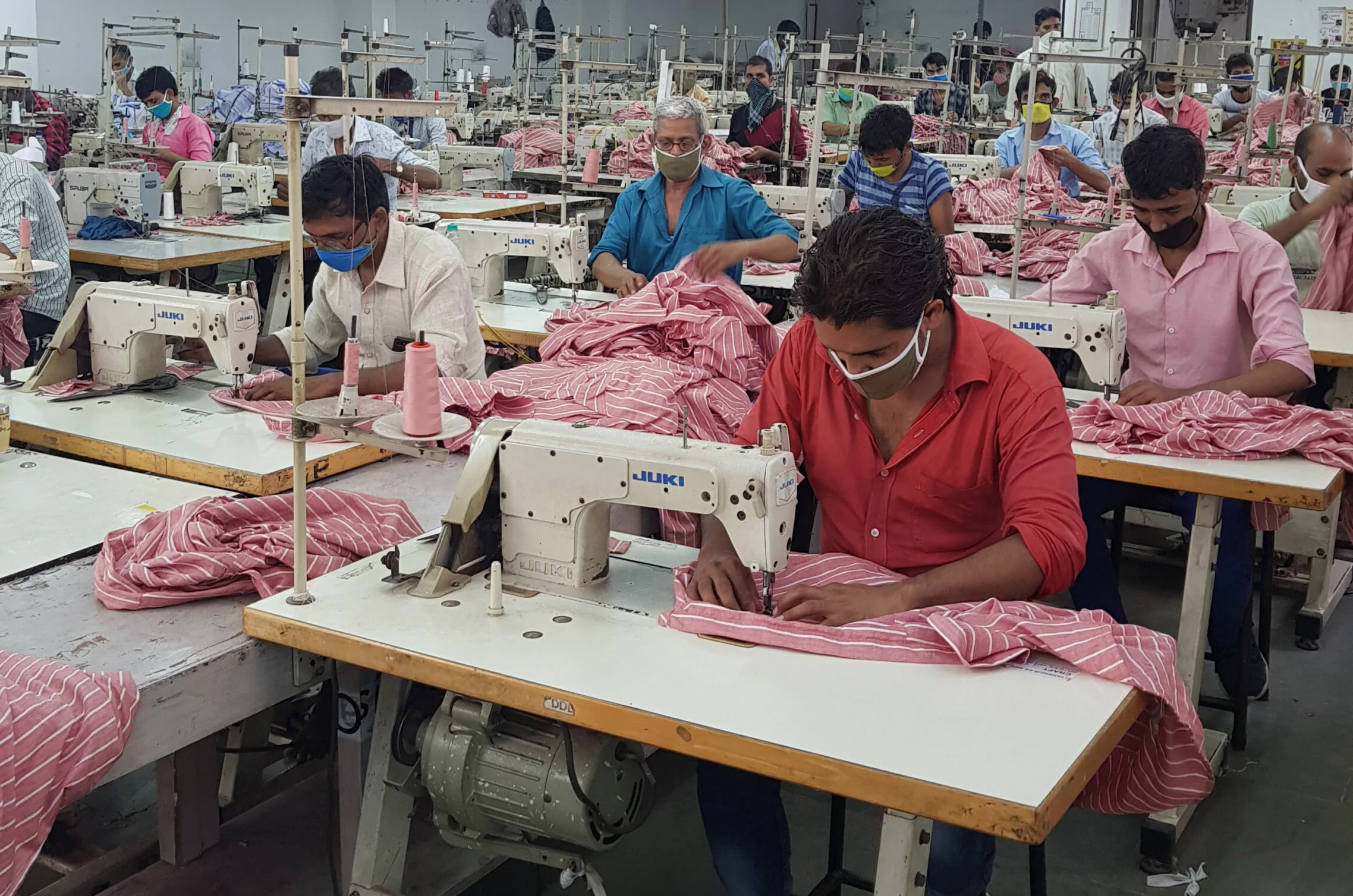 Indian garment factory workers operating sewing machines in Uttar Pradesh textile manufacturing workshop