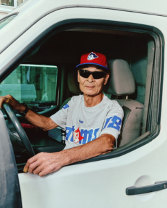 PALACE x Ebbets Field Flannels campaign shot, model wearing red baseball cap and printed grey tee