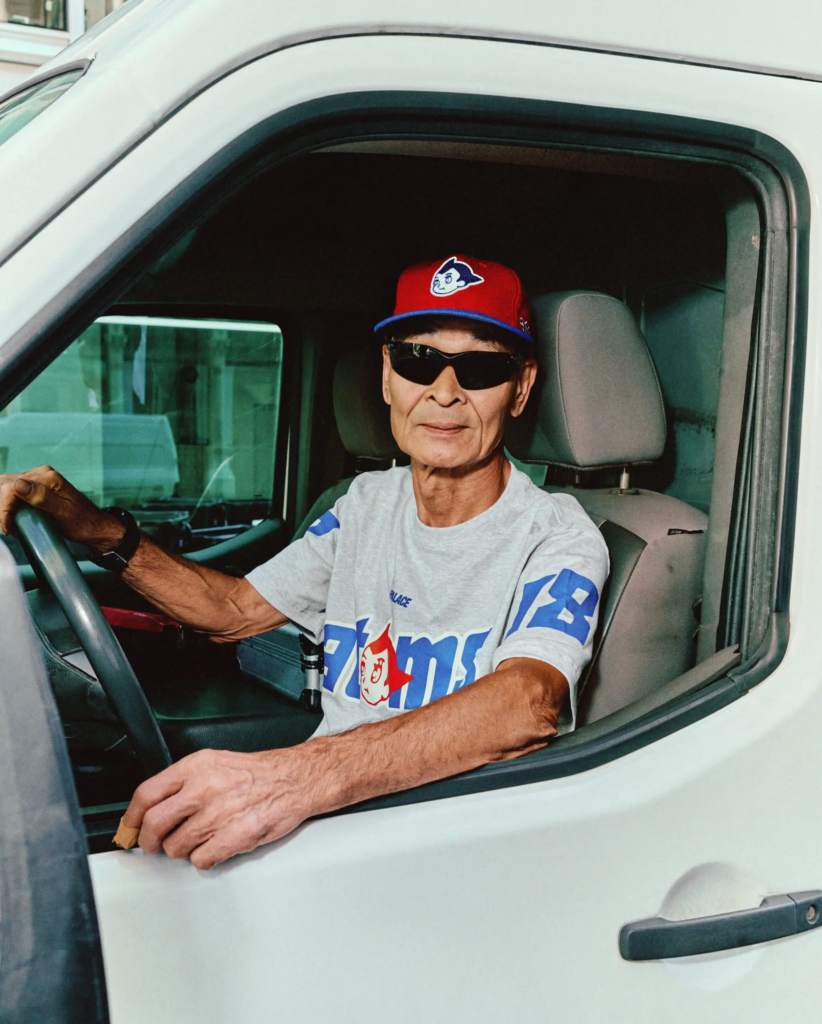 PALACE x Ebbets Field Flannels campaign shot, model wearing red baseball cap and printed grey tee