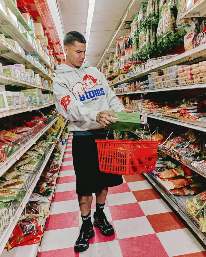 PALACE x Ebbets Field Flannels campaign, model wearing Atoms graphic hoodie inside grocery store
